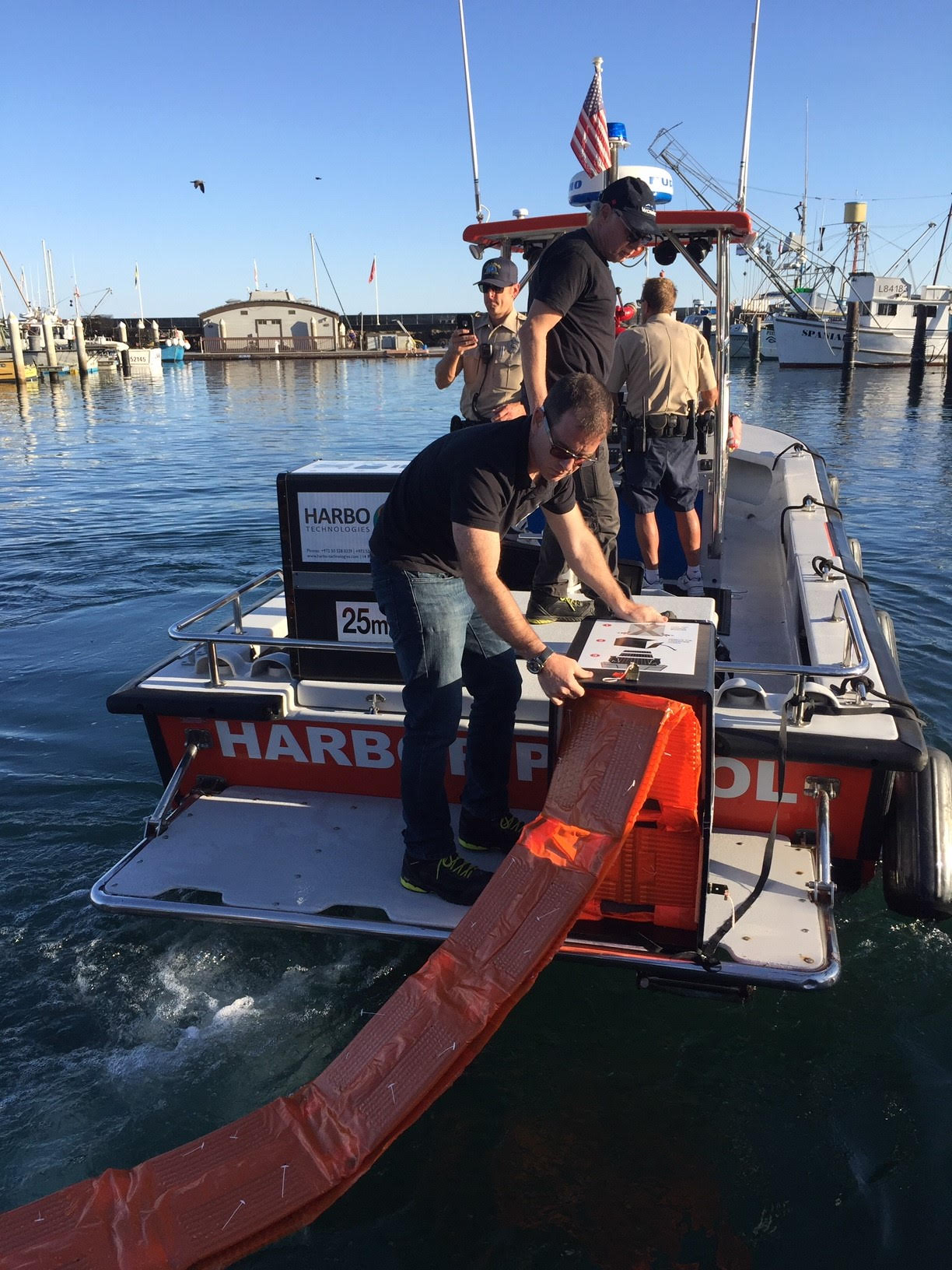 man deploying a HARBO boom from a boat