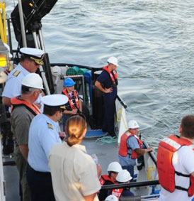 NAvy and coast guard men on a boat looking to the water