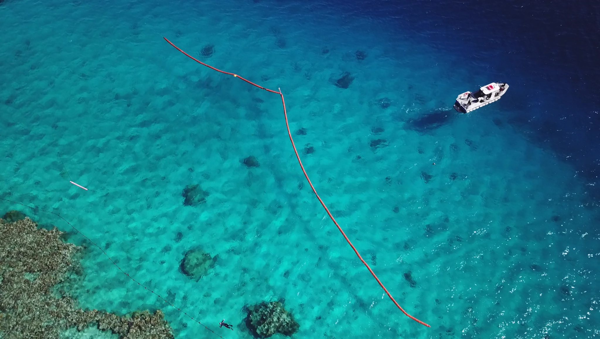 HARBO boom deployed over very clear water, small boat on the right